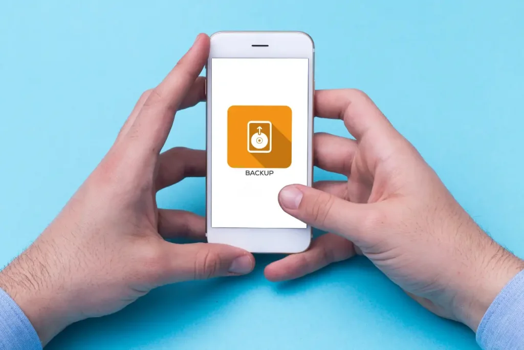 Mãos segurando um smartphone com o ícone de backup de disco rígido na tela
