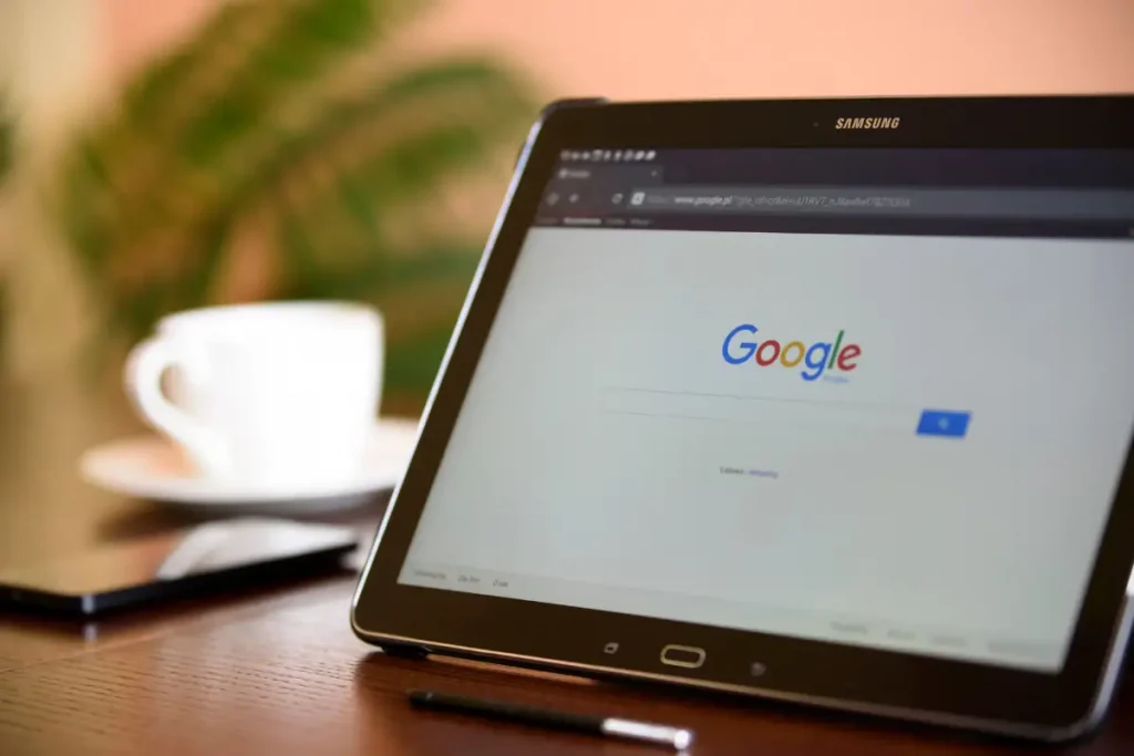 Tablet Samsung na horizontal exibindo a página inicial de pesquisa do Google com uma xícara de café